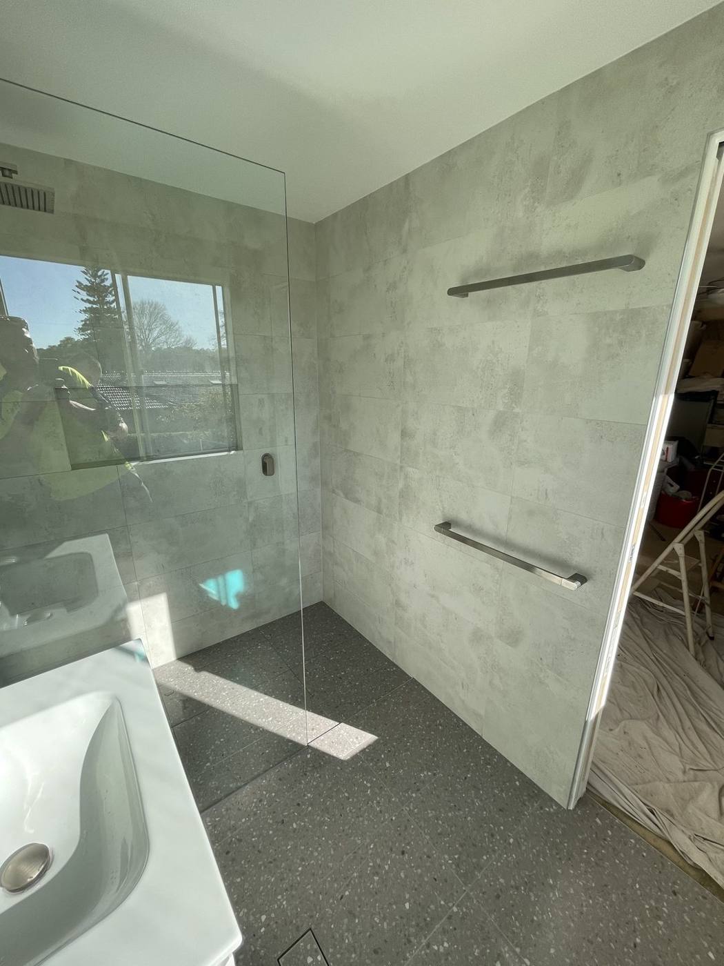 Finished frameless walk-in shower after renovation with heated towel rails, concrete-look wall tiles and terrazzo floor, Baulkham Hills by Loel Homes