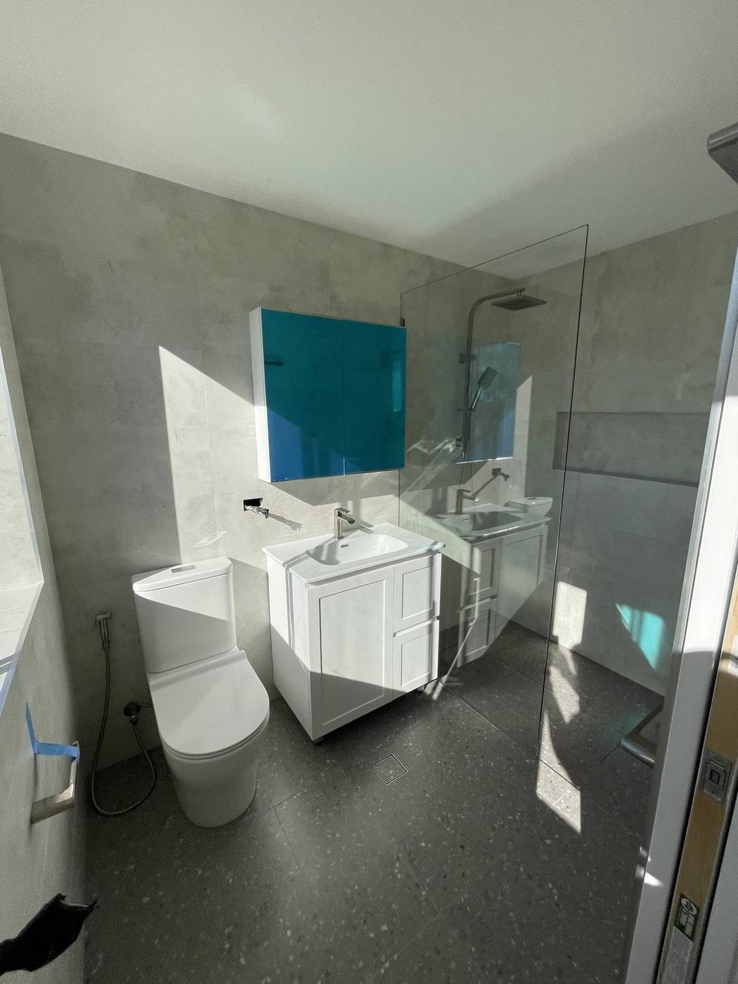 Finished modern bathroom after renovation with white shaker vanity, teal mirror cabinet, walk-in glass shower, concrete-look tiles and terrazzo floor, Baulkham Hills by Loel Homes