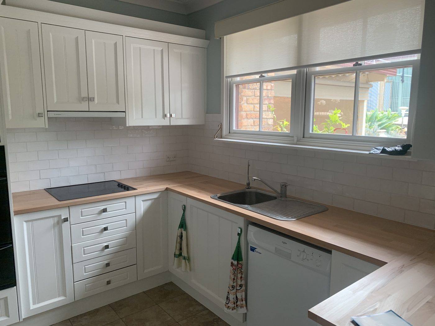 Renovated kitchen with timber benchtop and subway-tile splashback by Loel Homes