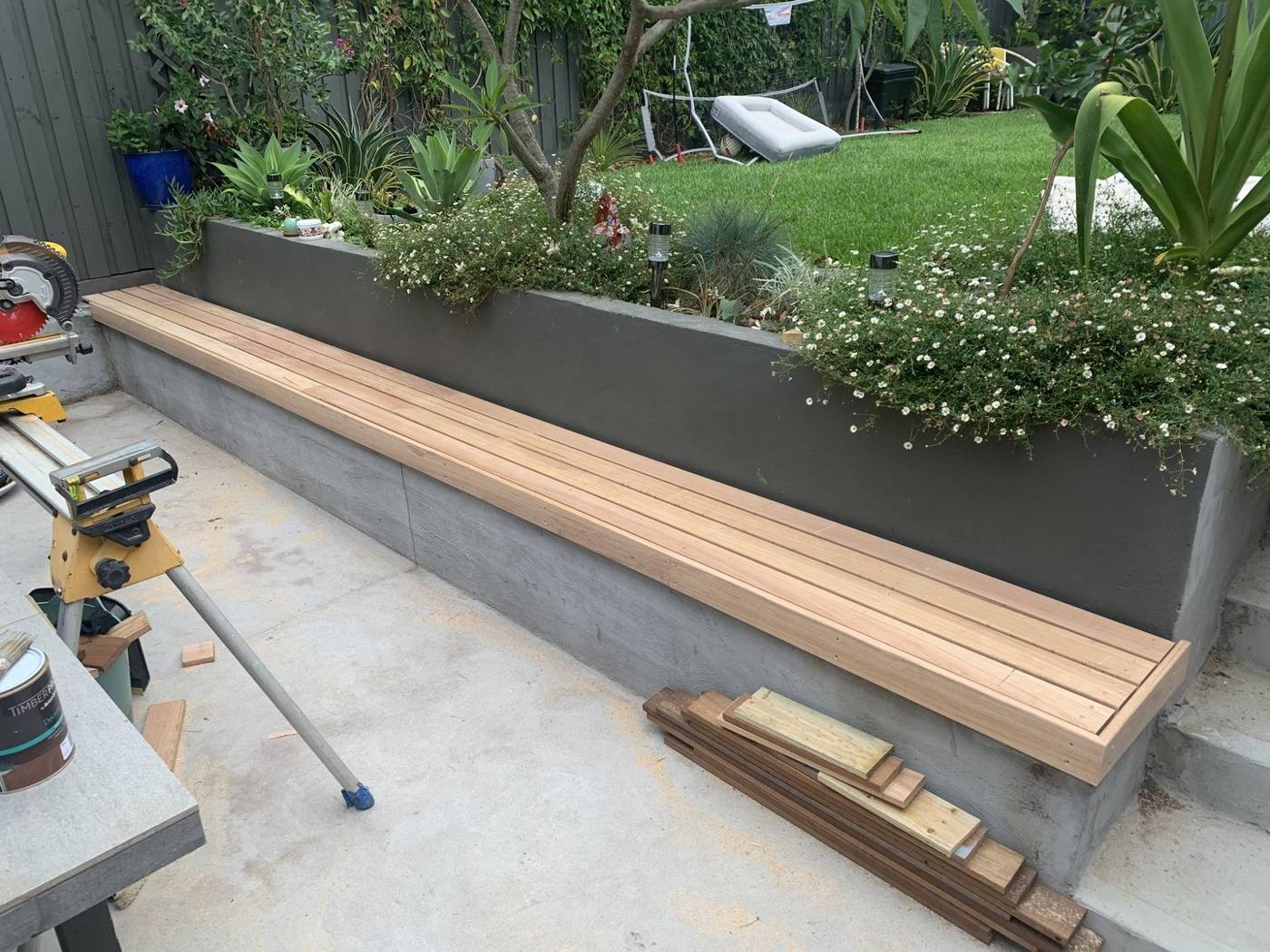 Finished timber bench seat running along the rendered planter wall by Loel Homes