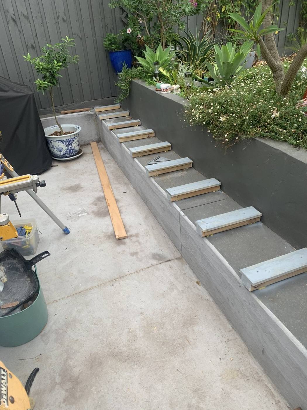 Timber bench seat being framed along a rendered garden planter wall in a courtyard by Loel Homes