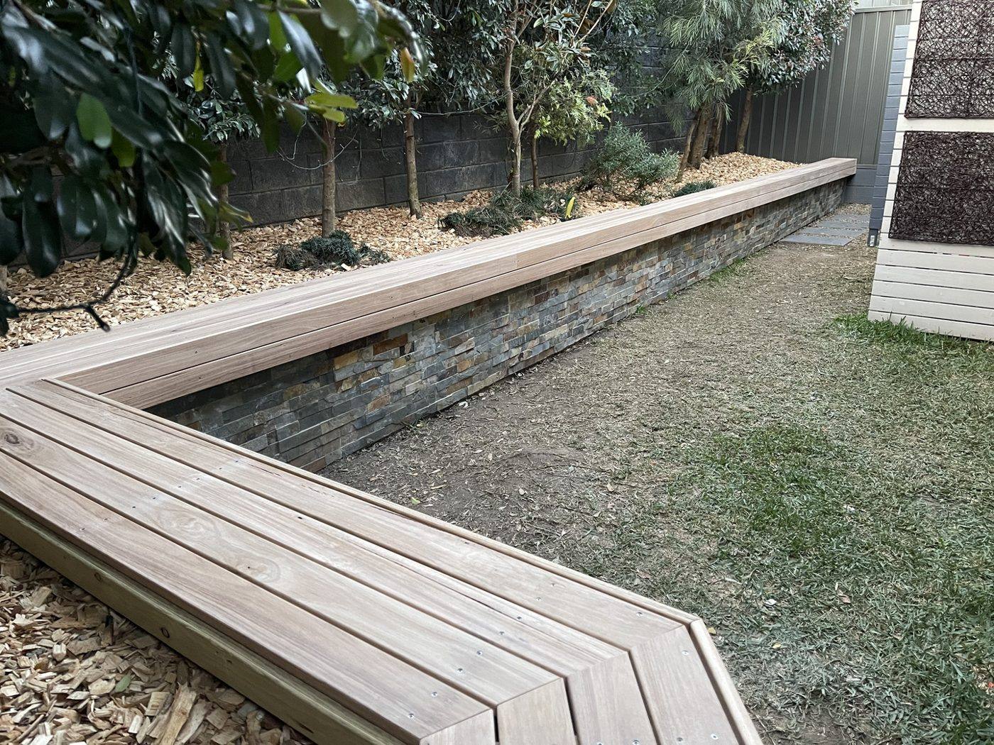 Close view of the finished timber bench turning the corner over a gravel border in a courtyard by Loel Homes