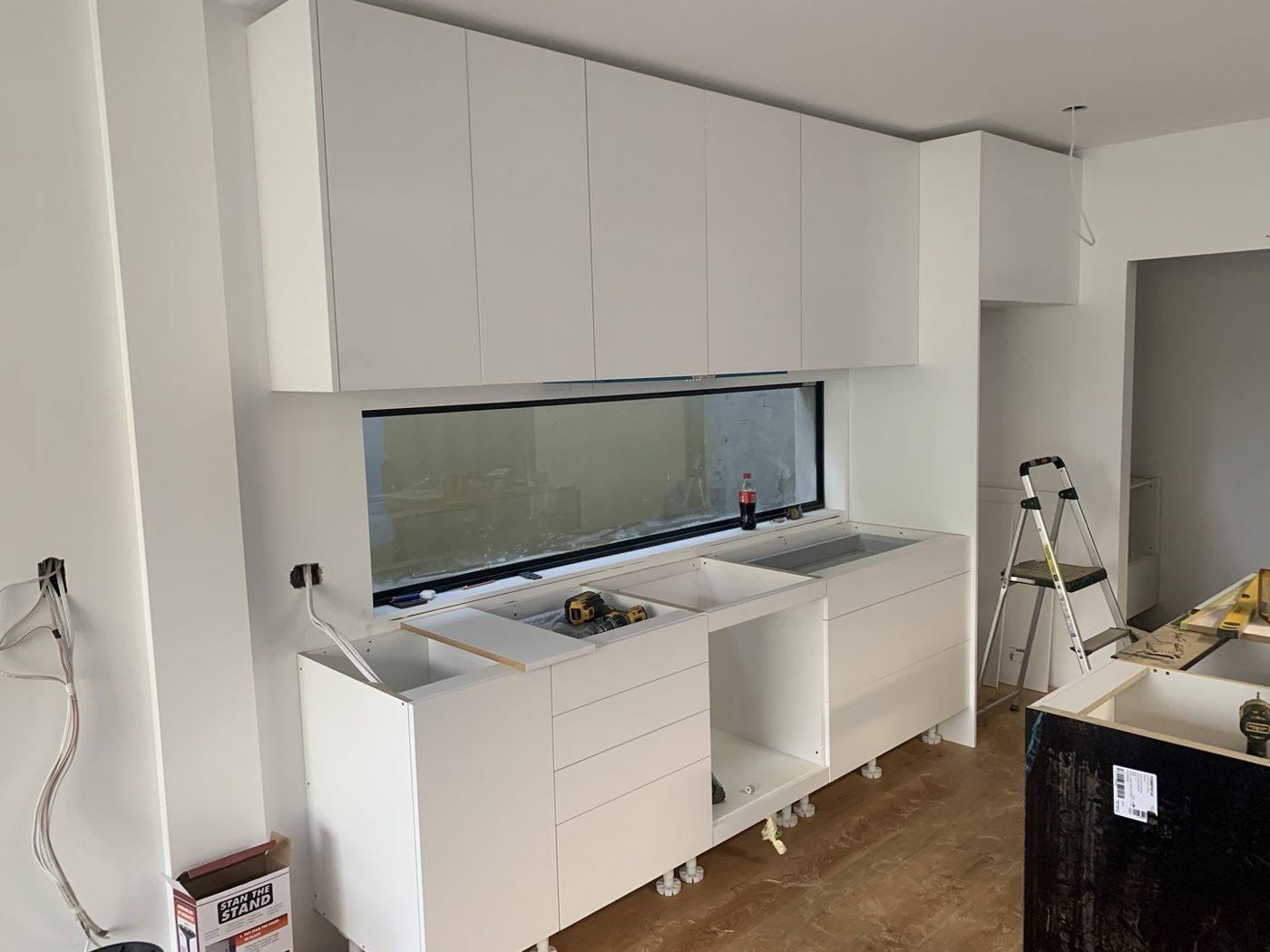 White kitchen base and overhead cabinets being installed with a long window splashback and appliance cut-outs open before benchtops, Dulwich Hill by Loel Homes
