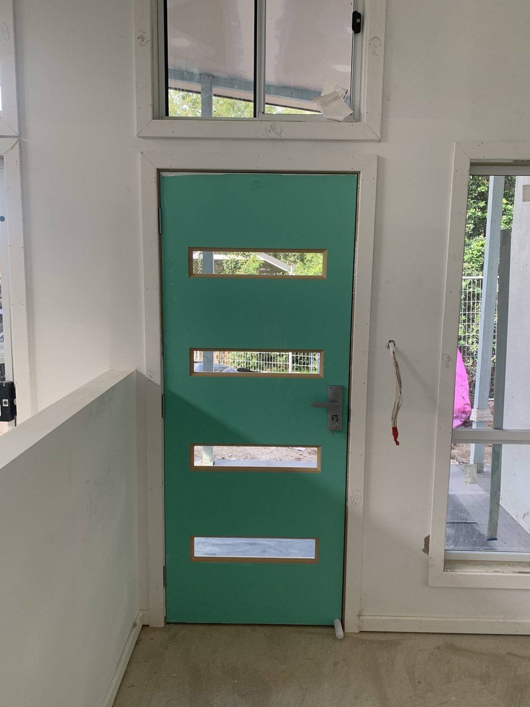 Same teal four-slot front entry door viewed from inside with the fanlight window above by Loel Homes