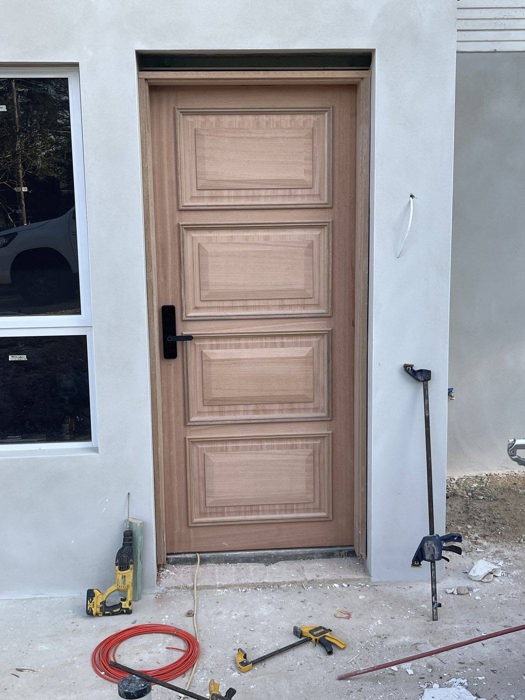 Timber-look oak panelled front entry door with black hardware on a brick home by Loel Homes