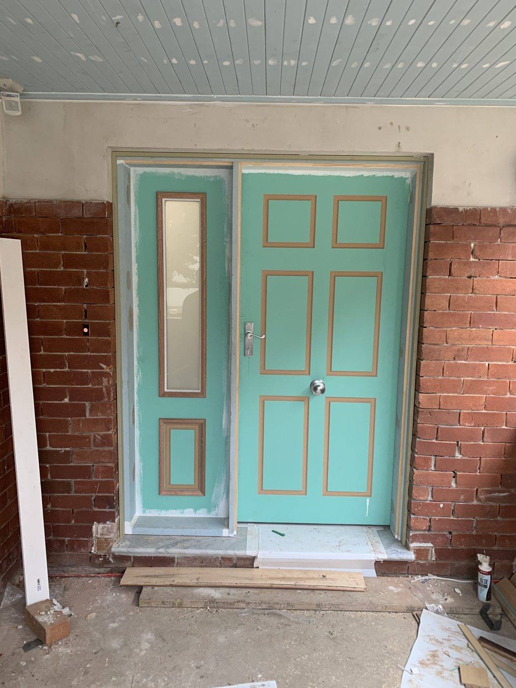 Teal colonial front entry door with a matching glass sidelight on a brick porch, closed front view by Loel Homes
