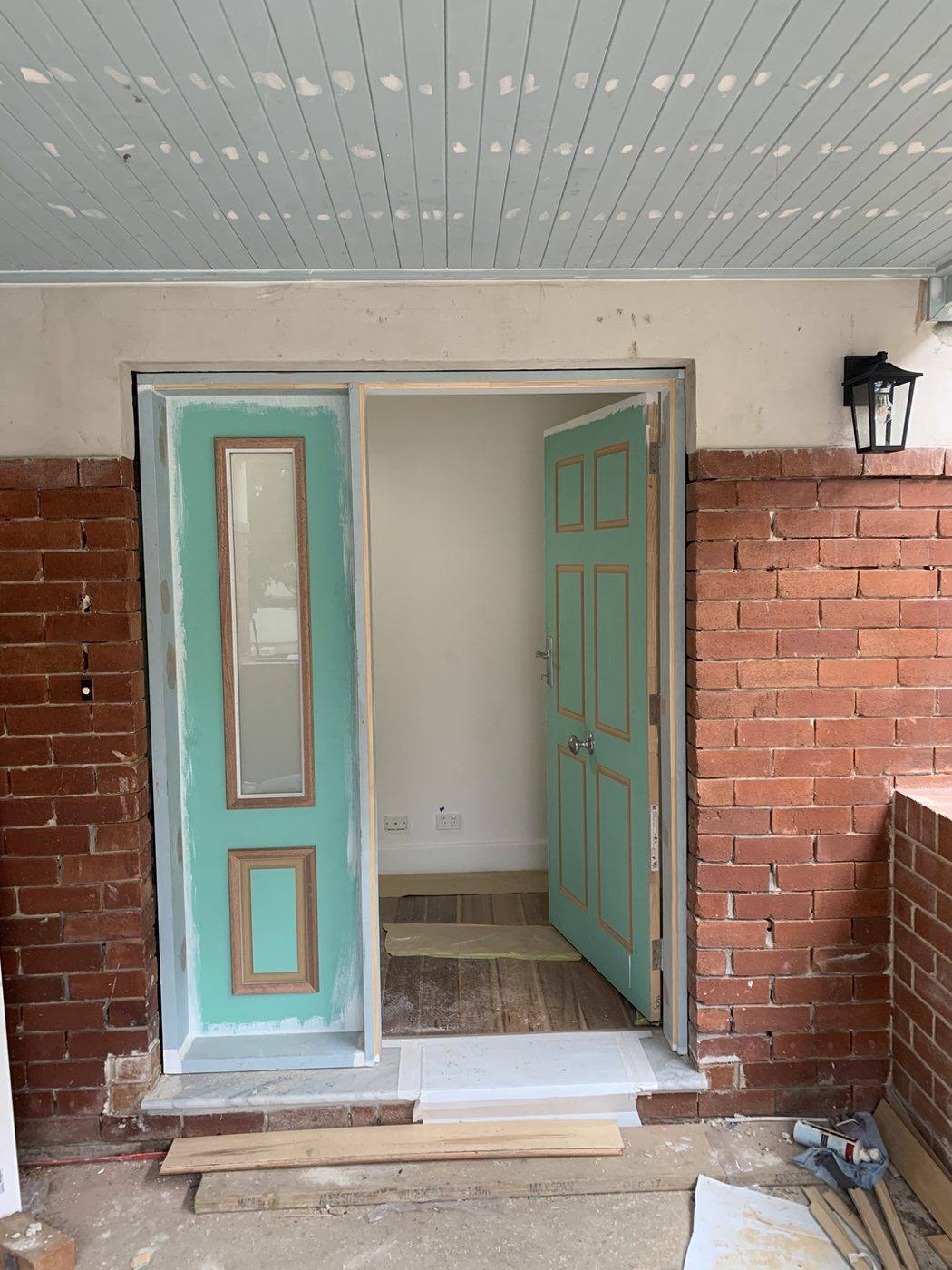 Same teal colonial front entry door with sidelight shown open into the hallway by Loel Homes