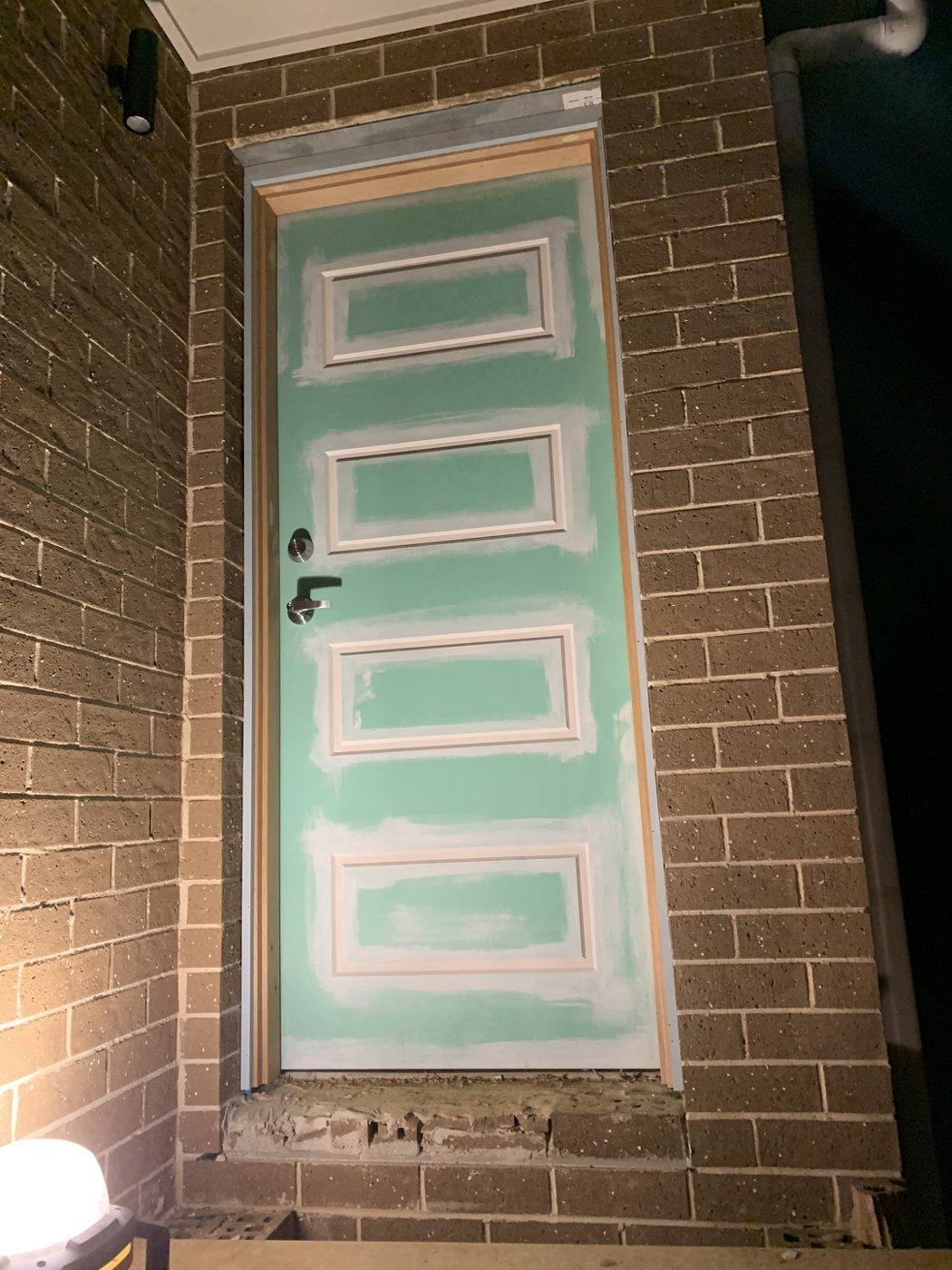 Teal five-panel colonial front entry door hung and finished on a brick home by Loel Homes