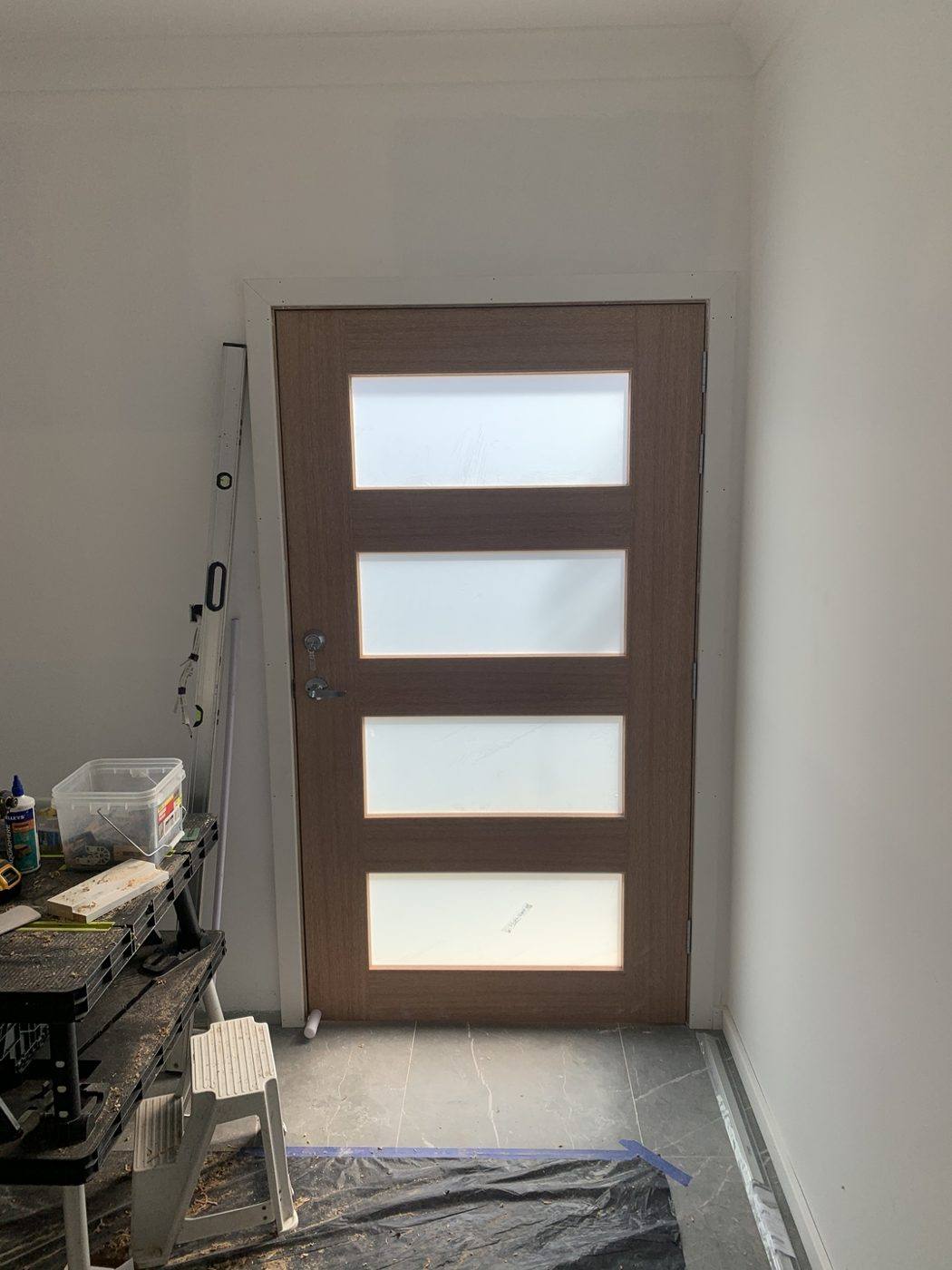 Same natural timber four-slot frosted-glass front entry door viewed from inside by Loel Homes