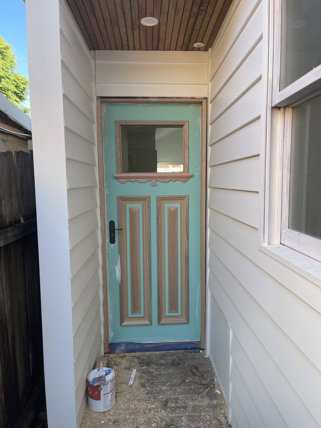 Same teal vision-panel front entry door viewed from the timber-lined porch outside by Loel Homes