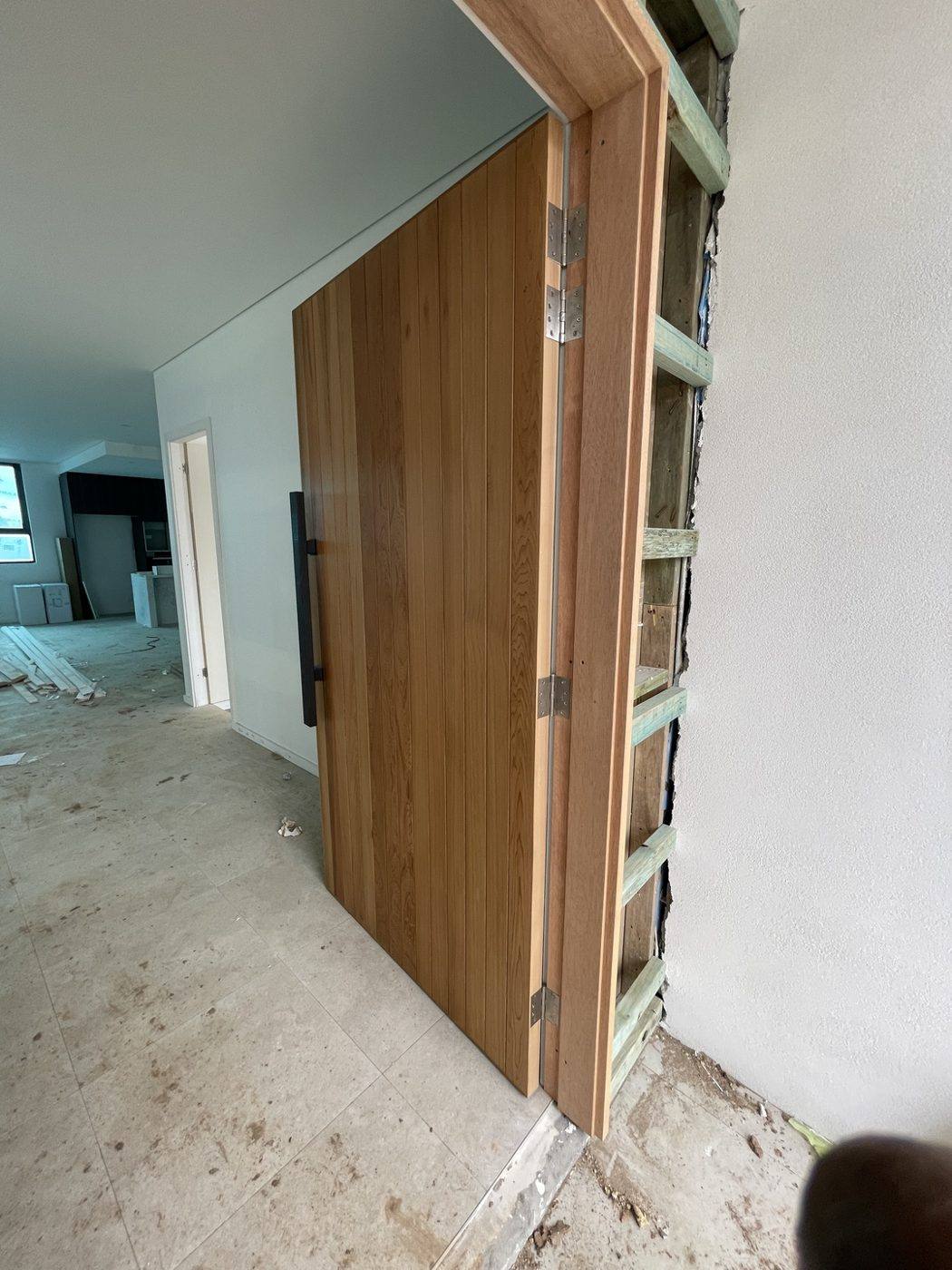 Oversized timber entry door swung open showing the concealed hinges, electronic lock and pull handle by Loel Homes