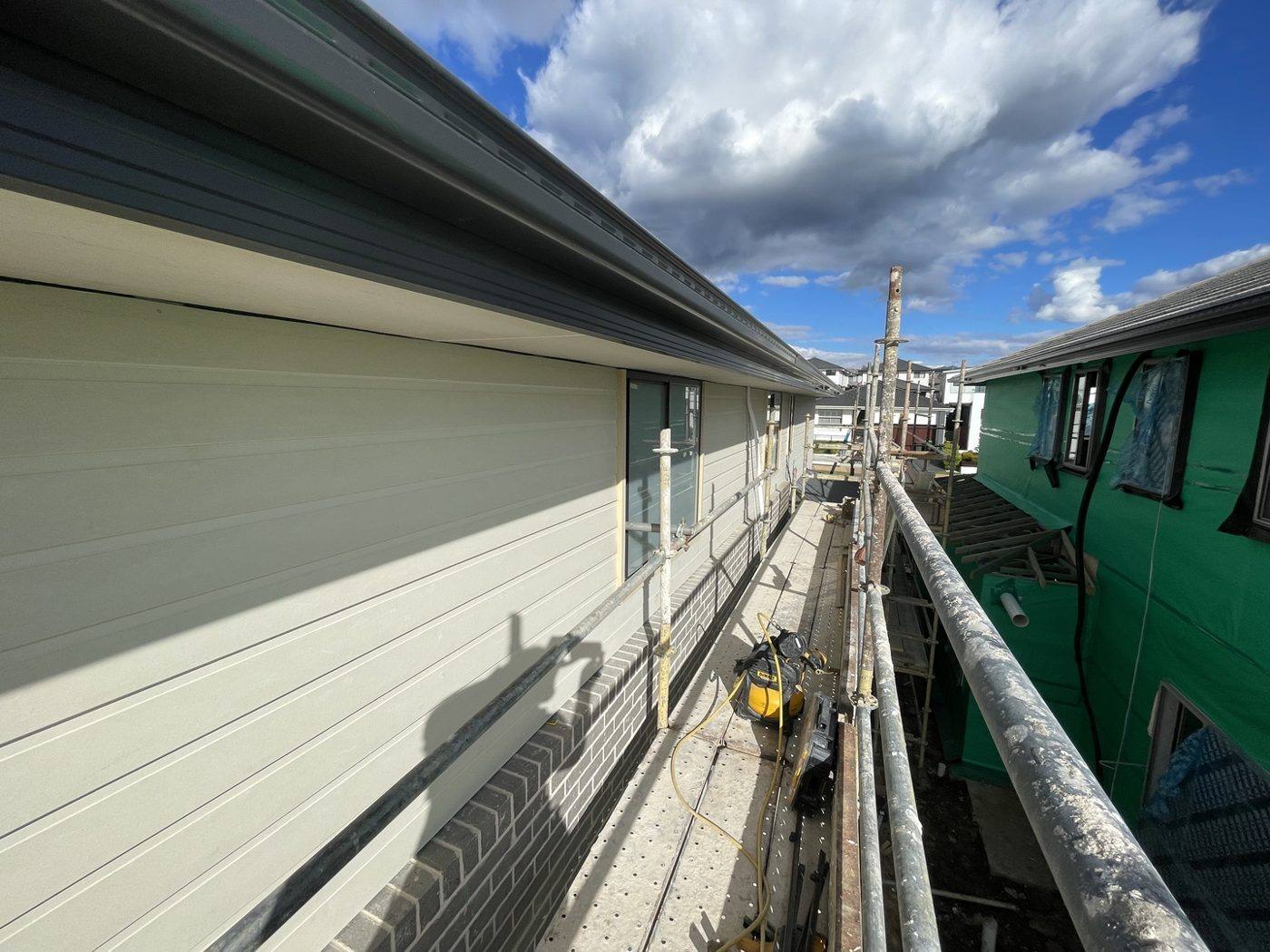 Long upper-level elevation part-clad in weatherboard with scaffold access, double-storey home by Loel Homes