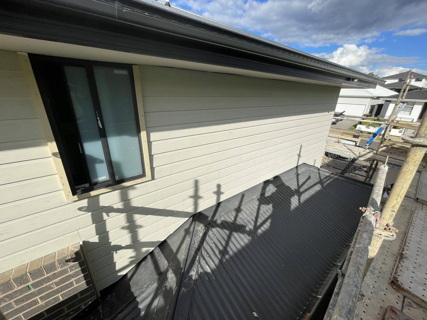 Over-roof view of the upper level clad in weatherboard beside the metal roof, double-storey home by Loel Homes