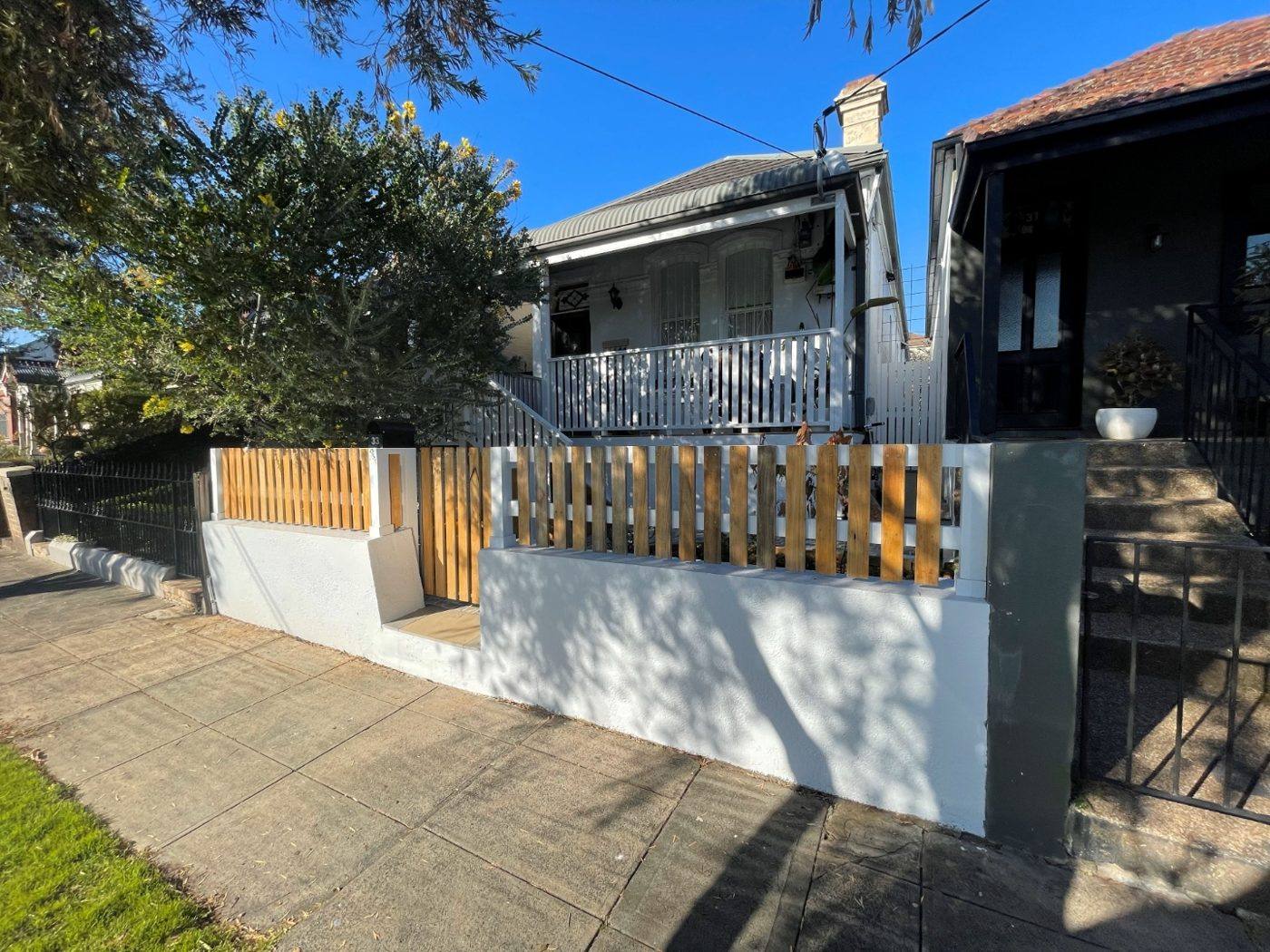 Finished front of a terrace with repainted charcoal facade, new rendered wall and white picket fence by Loel Homes