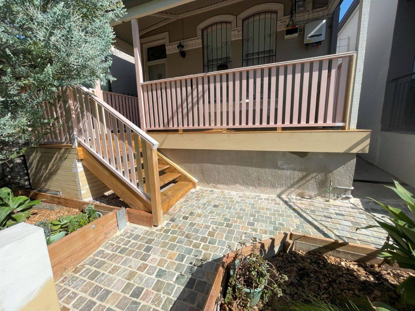 Rebuilt raised front verandah with new timber balustrade and stairs and fresh cobblestone paving before painting, terrace by Loel Homes