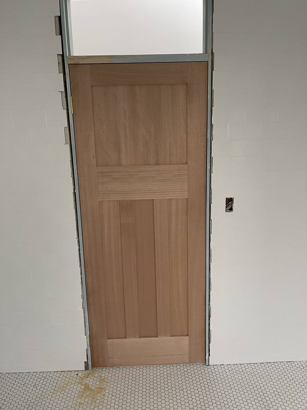 New solid timber internal door hung in a tiled room with highlight above, Inner West carpentry by Loel Homes