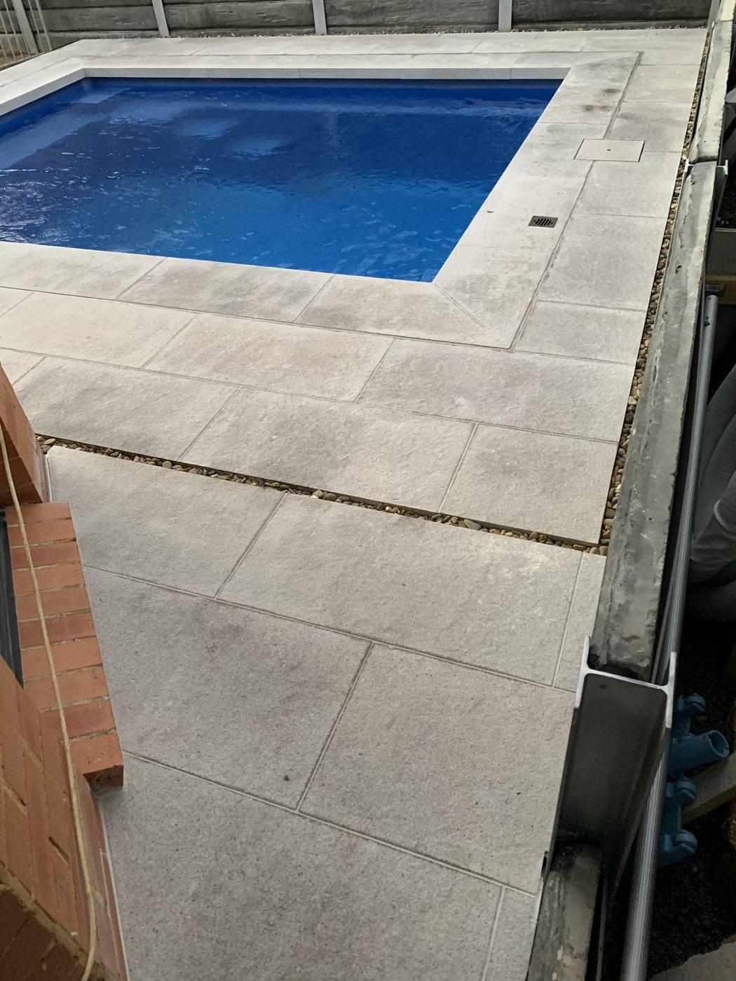 Sandstone-look coping being laid around a new square pool by Loel Homes