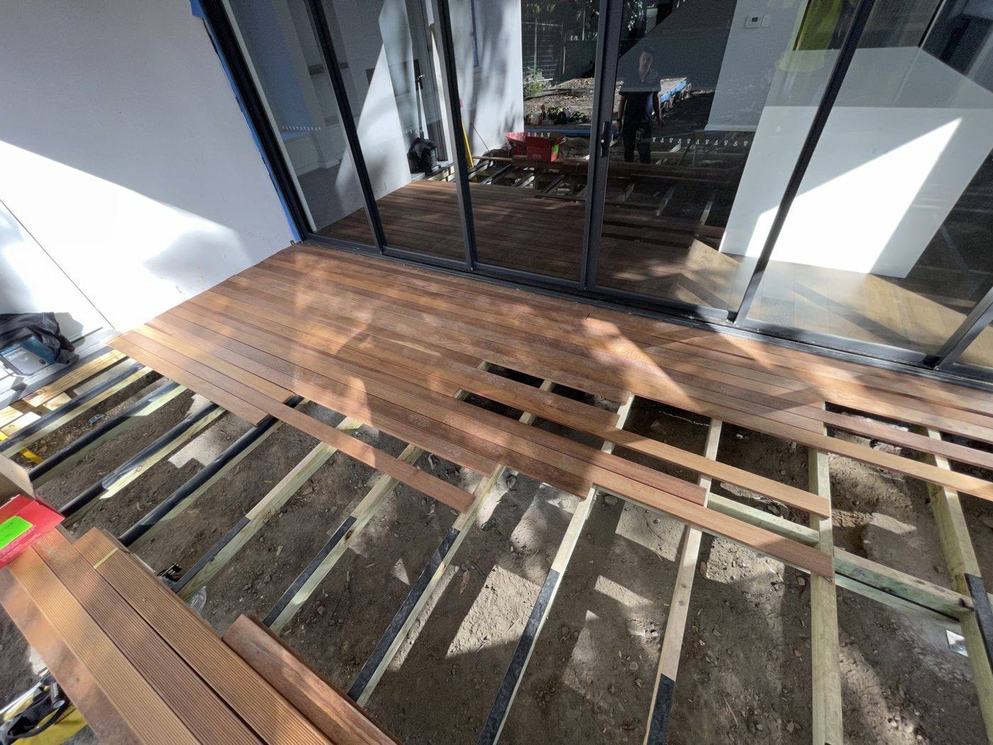 Hardwood deck boards being laid at the corner beside the glass sliding doors by Loel Homes
