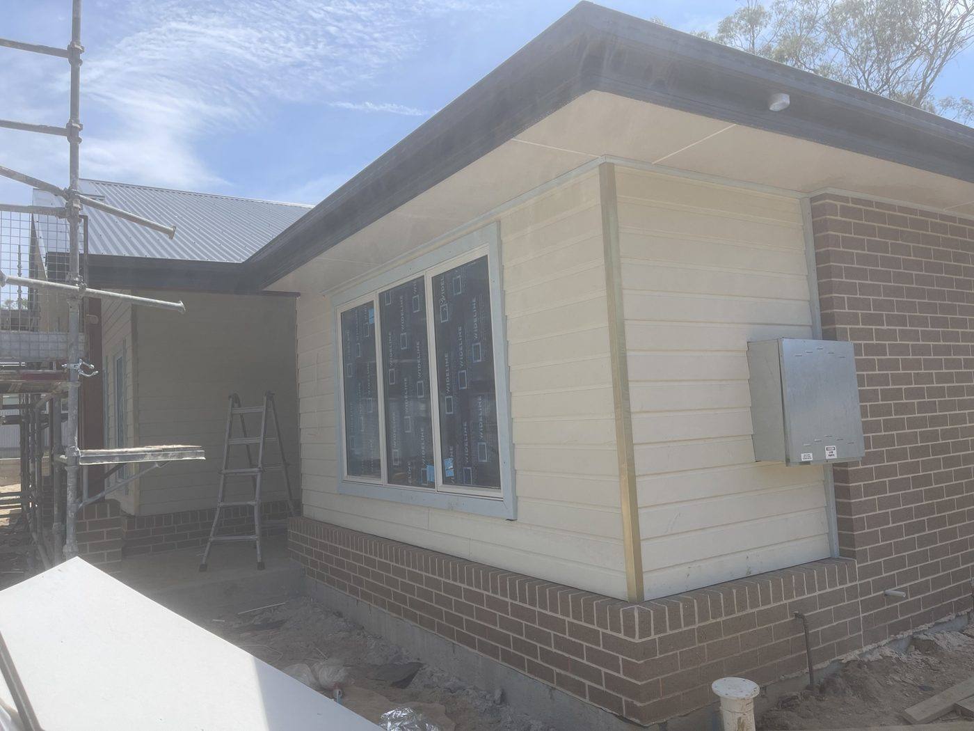 Corner elevation fully clad and painted cream over a brick base, rural home by Loel Homes