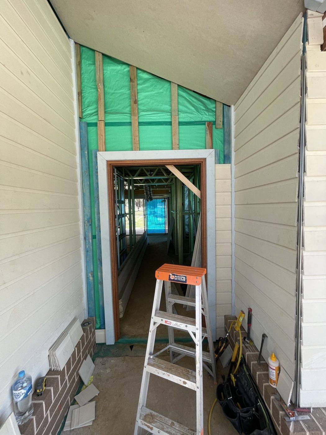 Weatherboard cladding going on around the entry recess with green sarking wrap still exposed, rural home by Loel Homes
