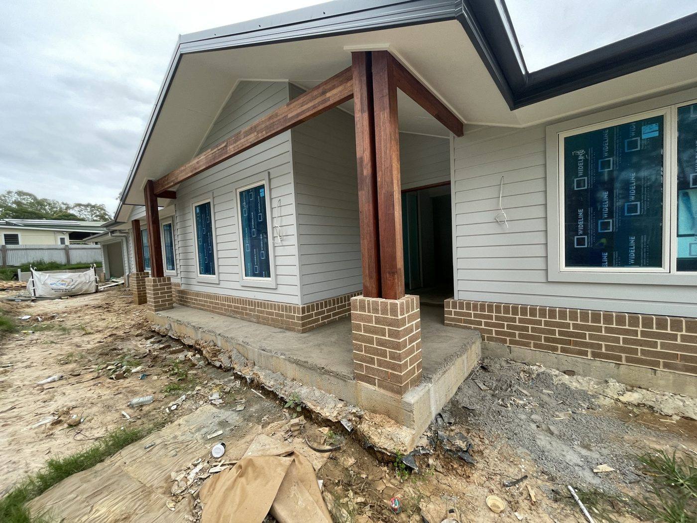 Front elevation near complete with timber feature posts and weatherboard cladding over a brick base, rural home by Loel Homes
