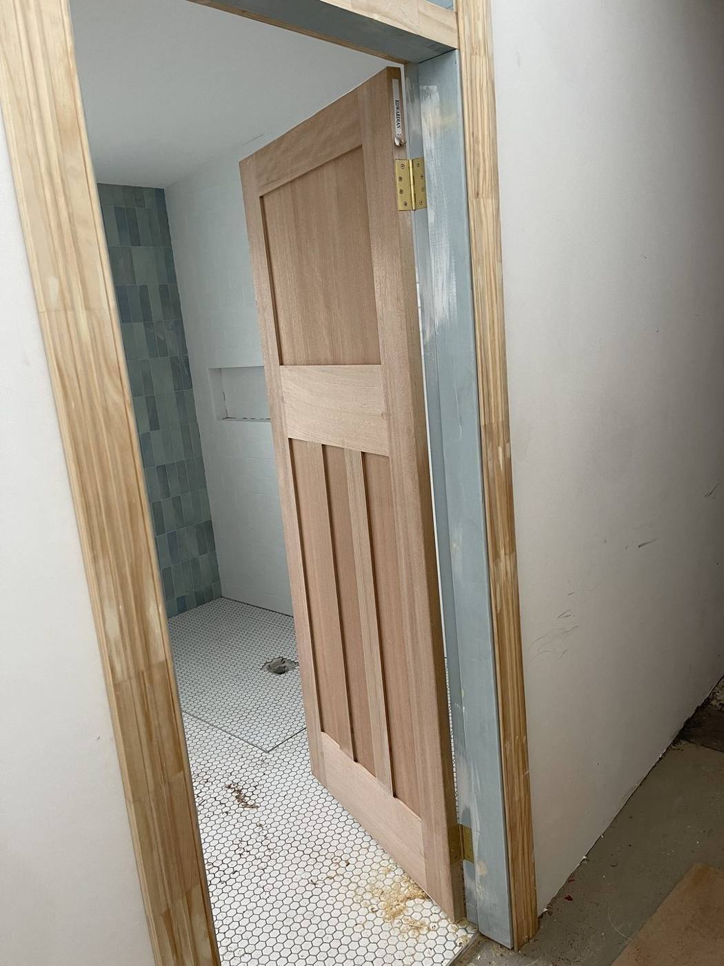 Solid timber shaker door hung on brass hinges to a tiled ensuite, heritage terrace carpentry by Loel Homes