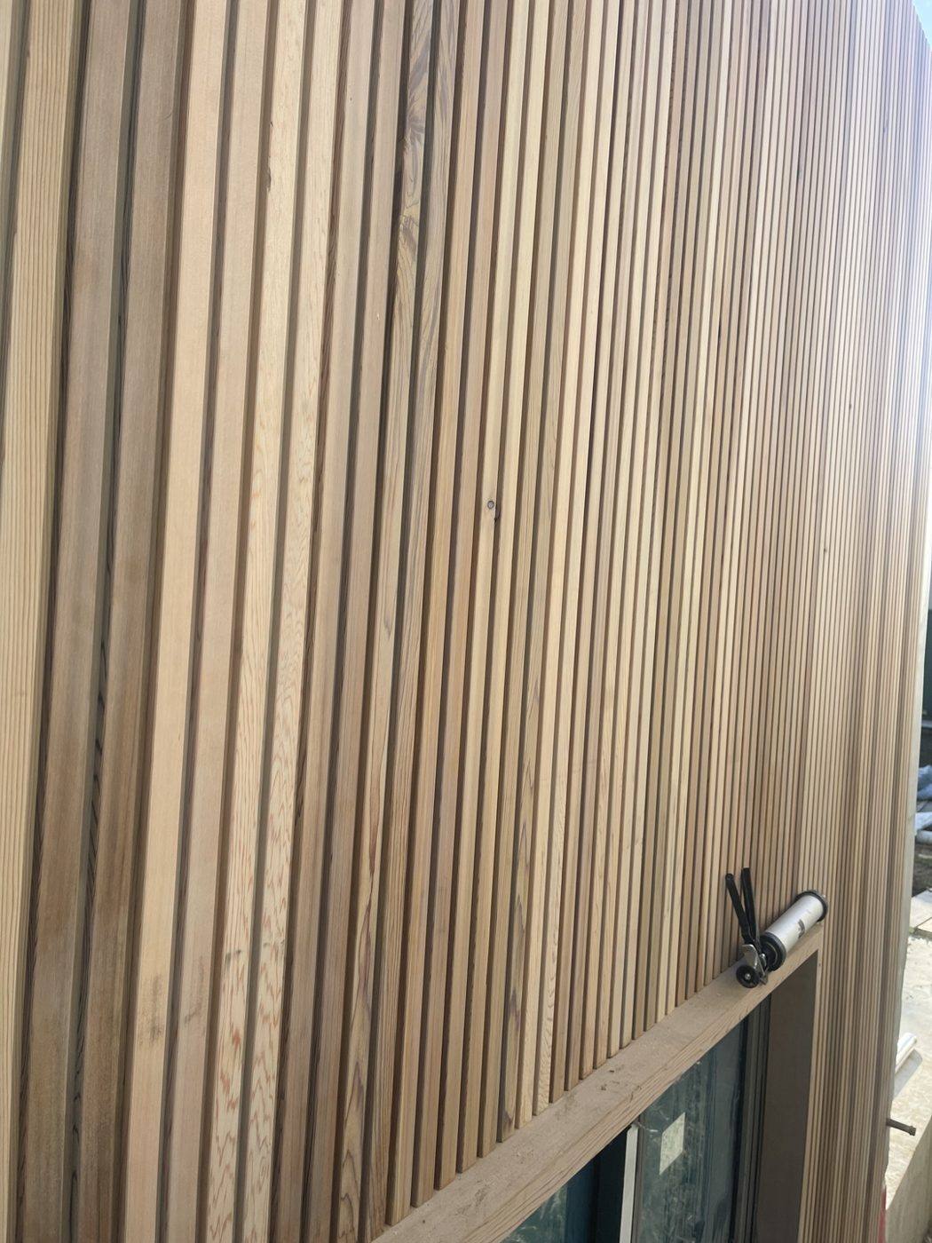 Close-up of installed pale timber batten cladding showing the grain and shadow lines, duplex by Loel Homes