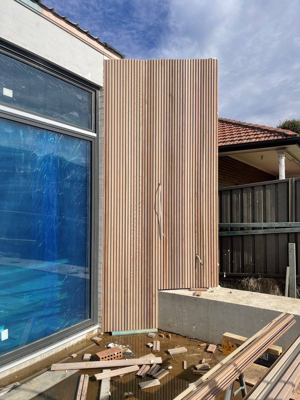Tall pale timber-clad blade wall beside full-height glazing, duplex by Loel Homes