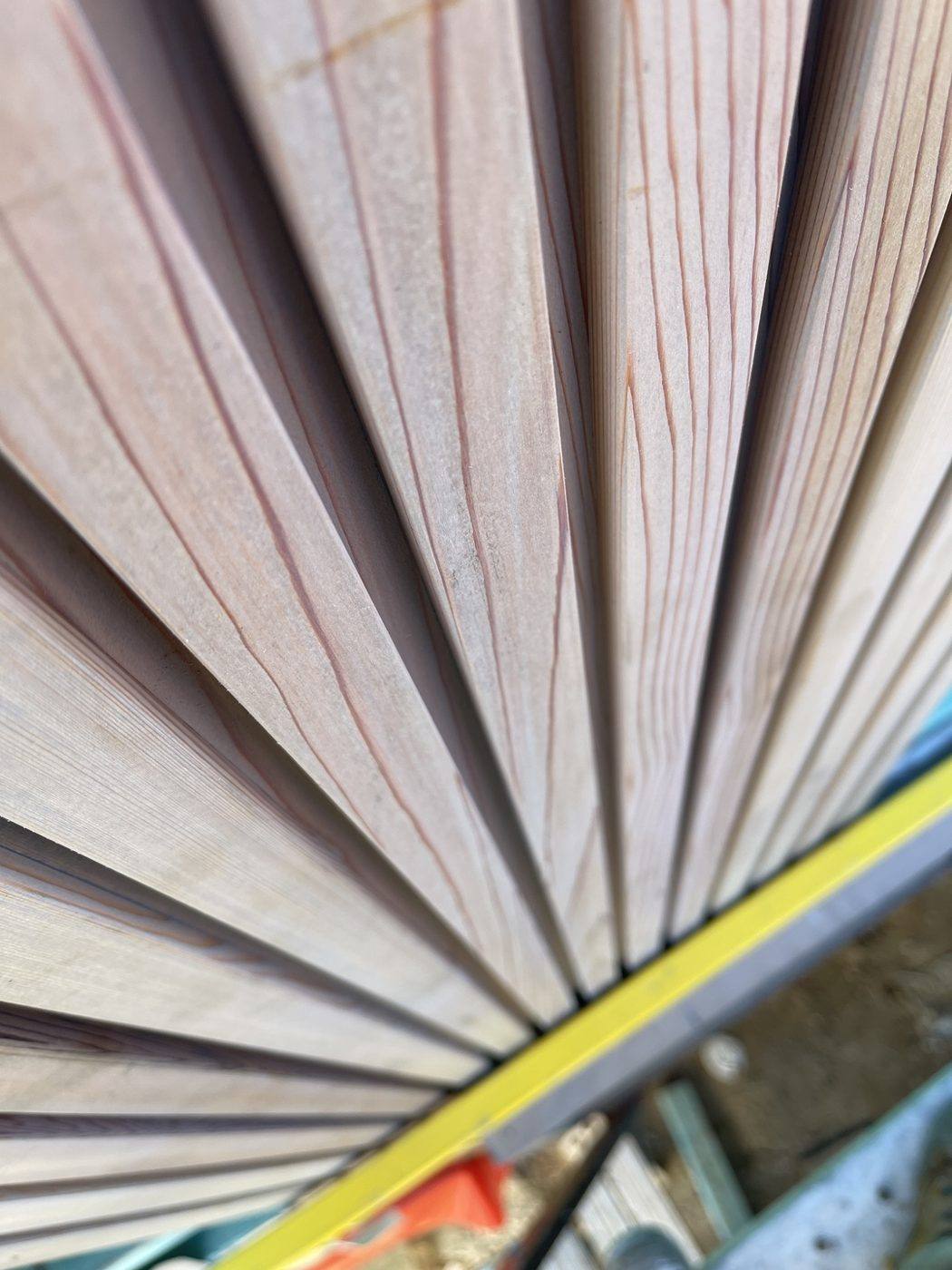 Fanned-out lengths of pale silvertop ash cladding boards showing the timber grain, Loel Homes