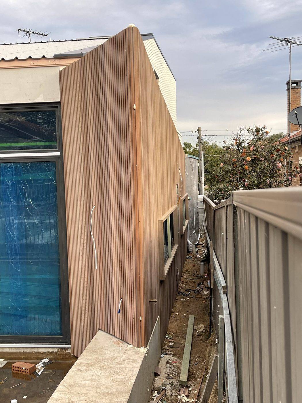Pale timber-clad two-storey wall running along the side boundary with windows, duplex by Loel Homes