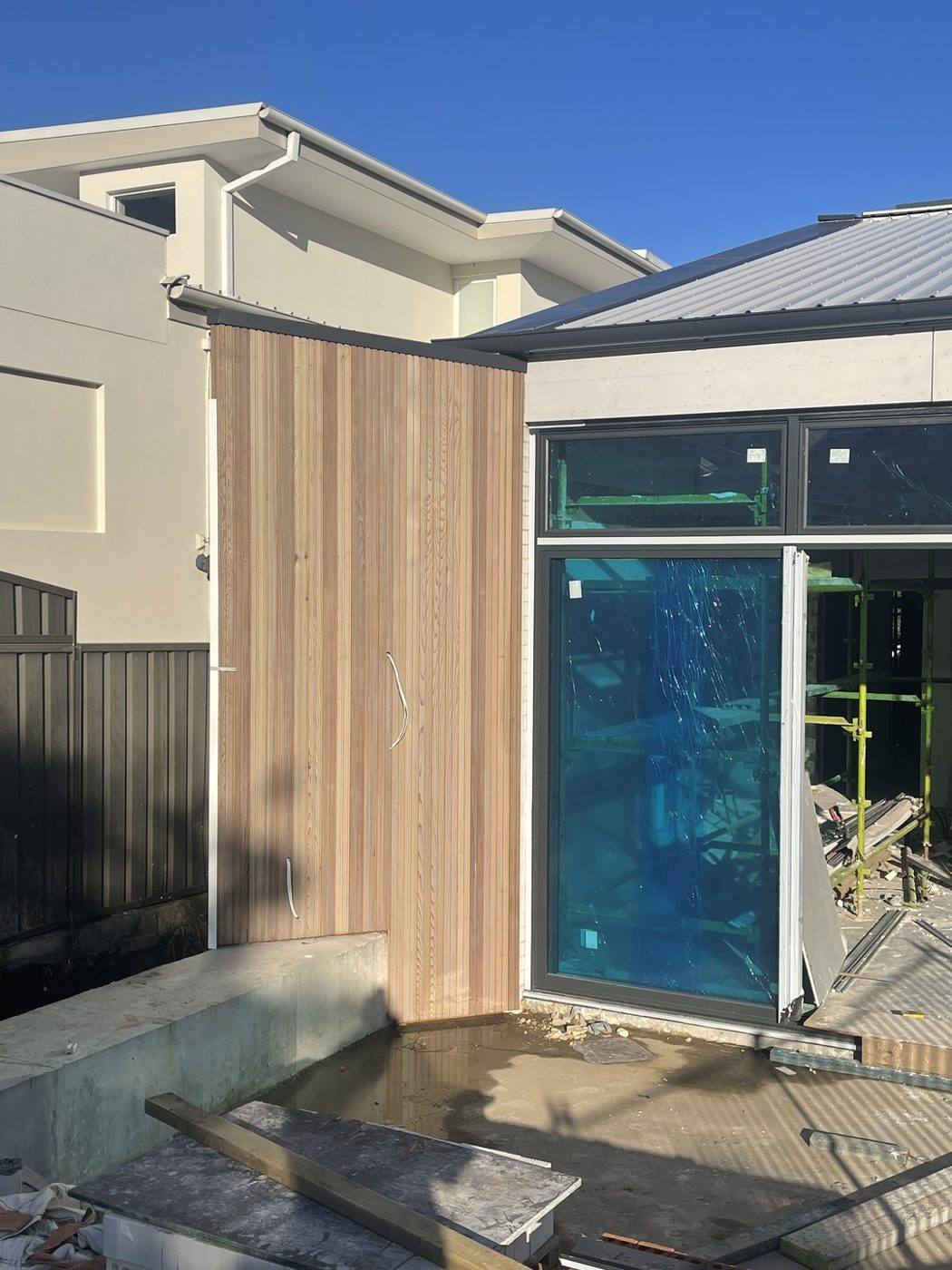 Pale timber-clad blade wall wrapping a corner next to full-height glass doors, duplex by Loel Homes
