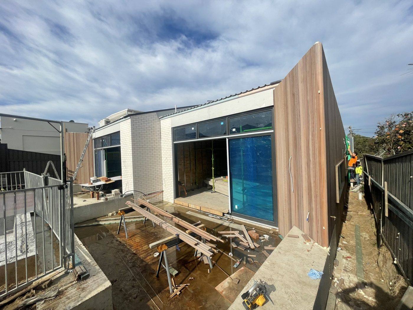 Wide view of a modern duplex rear elevation with a pale timber-clad blade wall and full-height glazing, Loel Homes