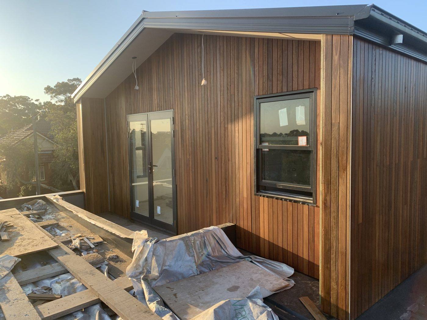 Corner of the timber-clad addition meeting the gutter and roofline with the neighbourhood beyond, luxury home by Loel Homes