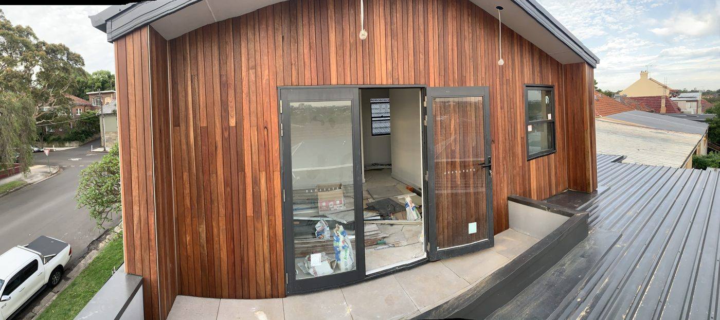 Finished warm timber-clad wall with glass doors opening onto a new deck, luxury home by Loel Homes