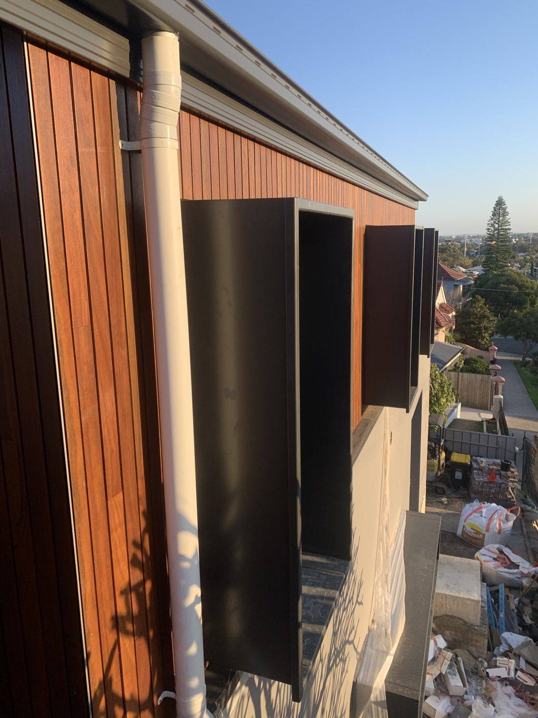 Warm timber cladding with black steel privacy blades and a neat downpipe run to the gutter, luxury home by Loel Homes