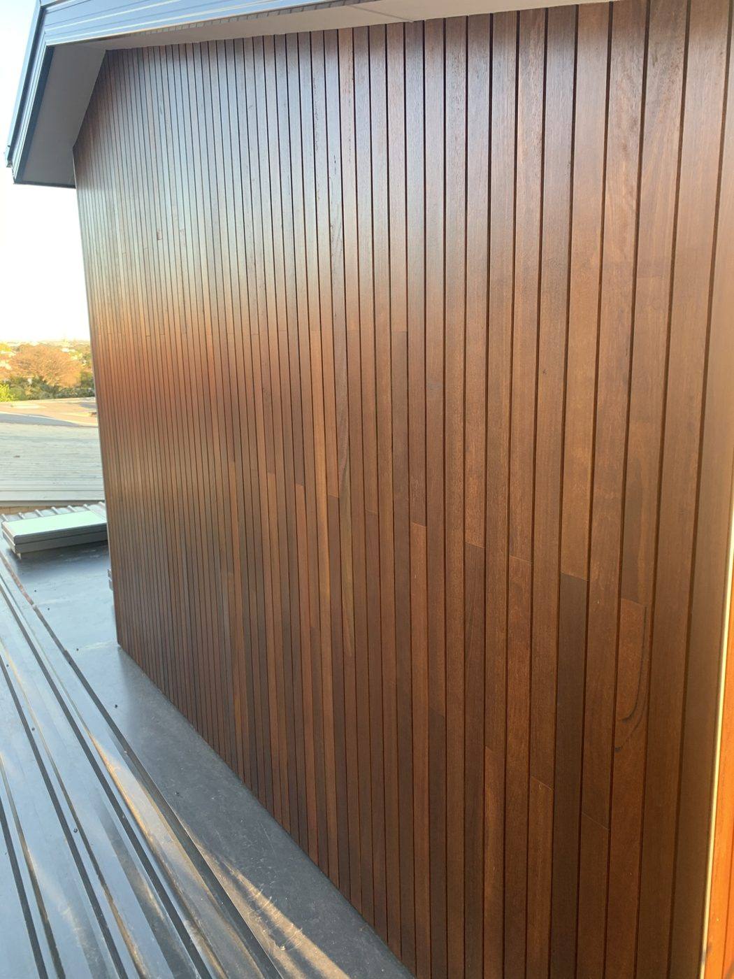 Close detail of oiled spotted gum vertical cladding meeting a black window frame, luxury home by Loel Homes