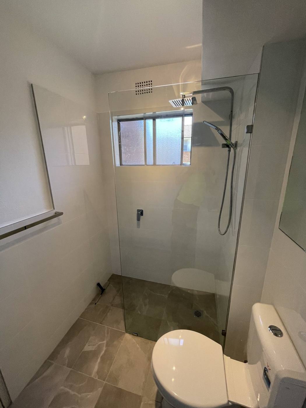 Finished frameless glass shower with rain head and toilet on grey stone-look tiles, Top Ryde by Loel Homes