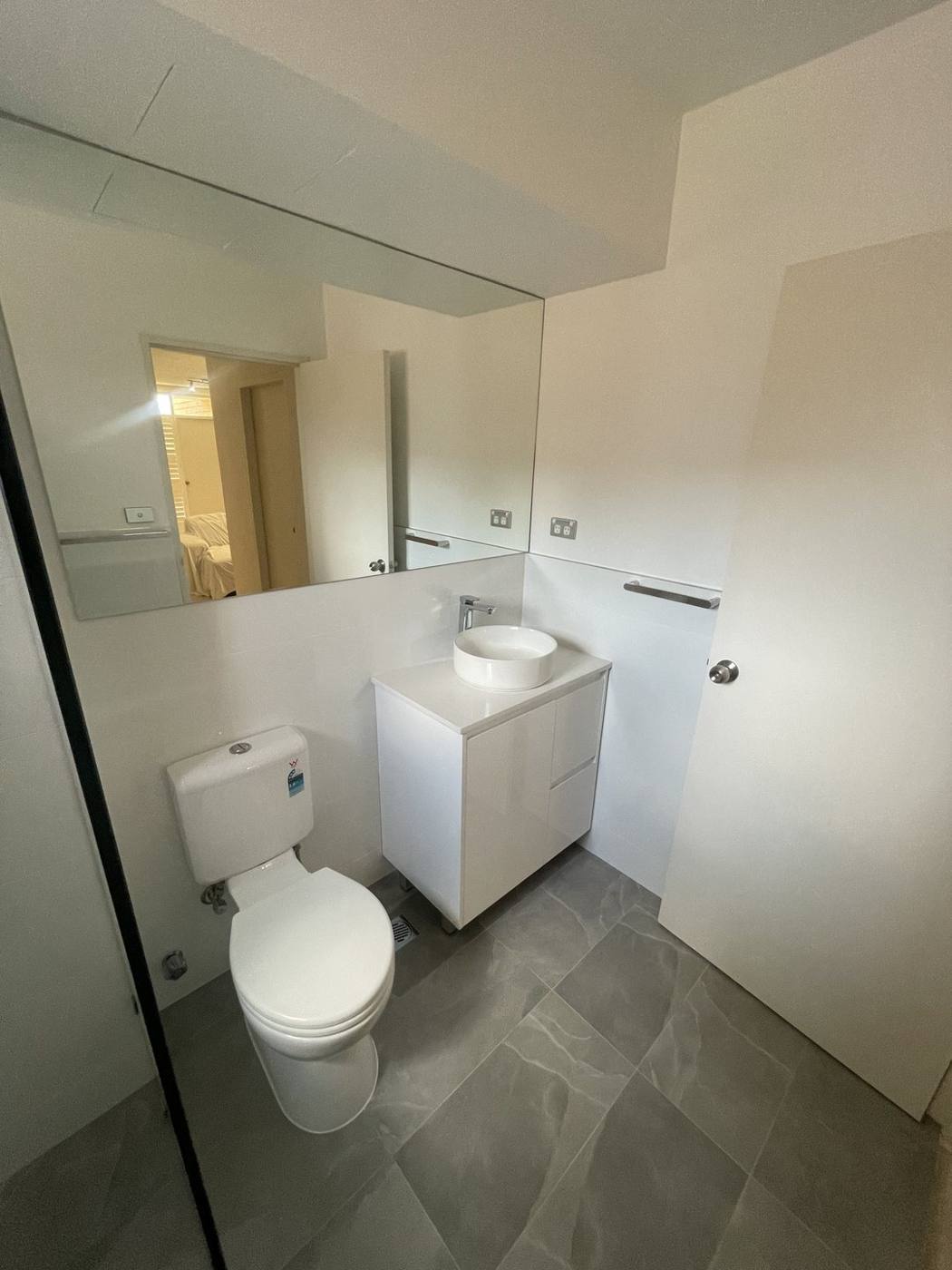 Finished bathroom vanity, toilet and large mirror with white walls and grey floor tiles, Top Ryde by Loel Homes