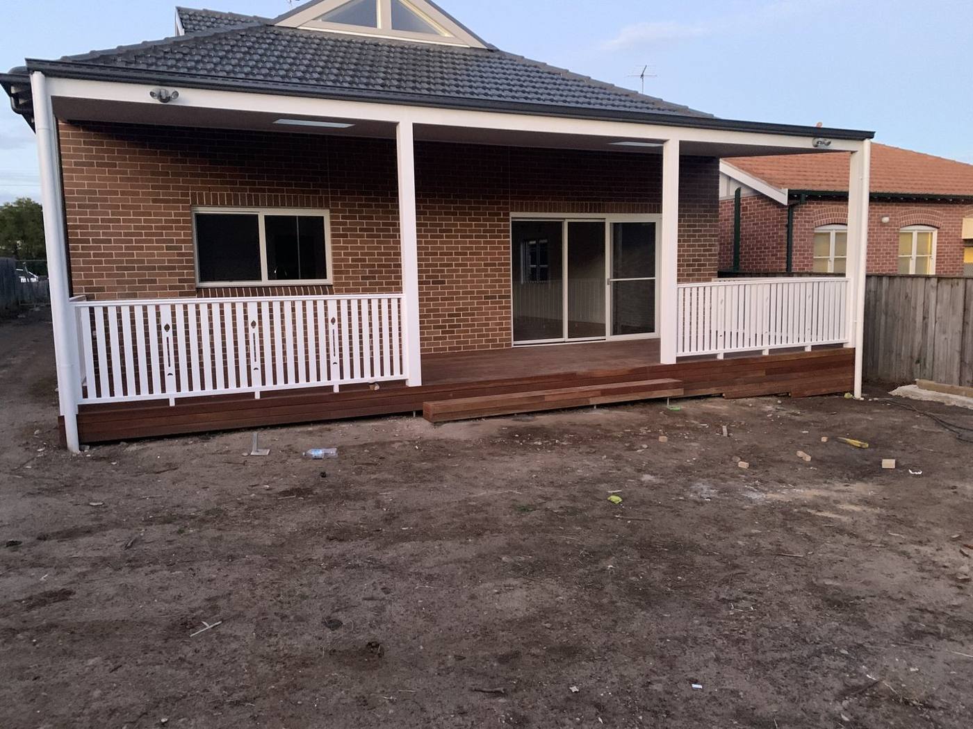 Finished covered verandah deck with white balustrade on a red-brick home by Loel Homes